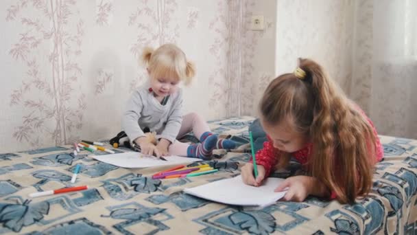 Twee kleine meisjes op het bed liggen en tekening iets — Stockvideo