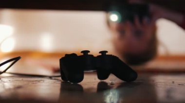 Joystick yatağın altında. Kız onu arıyor ve onu yakalıyor