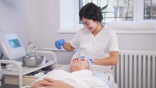 Traitements anti-âge. Mettre du polyéthylène sur le visage. Souriant — Video