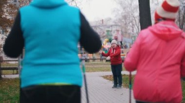 Yaşlı bir kadına el sinyal verir ve iki yaşlı kadın başlar sopa Nordik yürüyüş yürüyüş