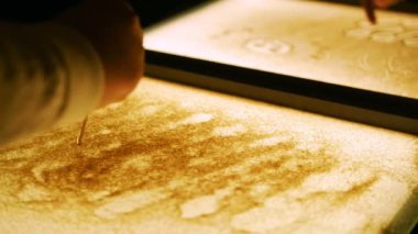 Bir kum ile ekranda çizim. Çizim ince bir sopa ile. Yakın çekim