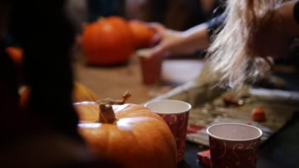 Fiesta de Halloween. Un grupo de personas sentadas y hablando alrededor de las calabazas — Vídeos de Stock