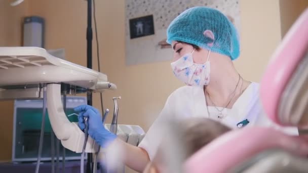 Tandheelkunde. Vrouwelijk tandarts zet uit het instrument en praat tegen de baby patiënt — Stockvideo