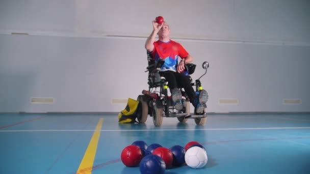 Un handicapé en fauteuil roulant. Lancer une petite boule bleue. Boccia. Bleu, rouge, blanc — Video