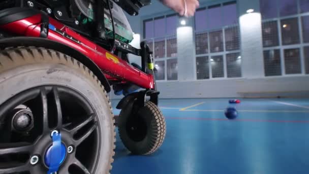Een gehandicapte man in een rolstoel spelen van boccia. Hand in het frame — Stockvideo
