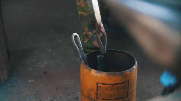 Kovář si horké kleště do vody. Mid shot. — Stock video