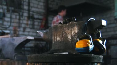 Demirci detay bir çekiç ile bir form almak. Gürültü kulaklık örs üzerinde