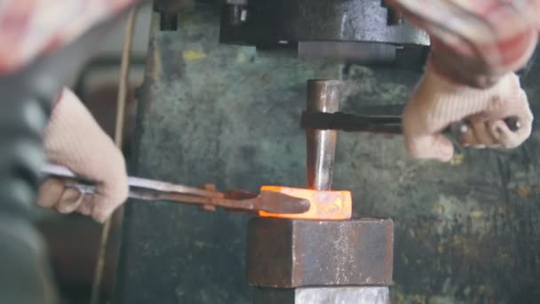 Кузнец за работой с электрическим молотком на наковальне, делает отверстие в красной горячей стали, ремесла — стоковое видео