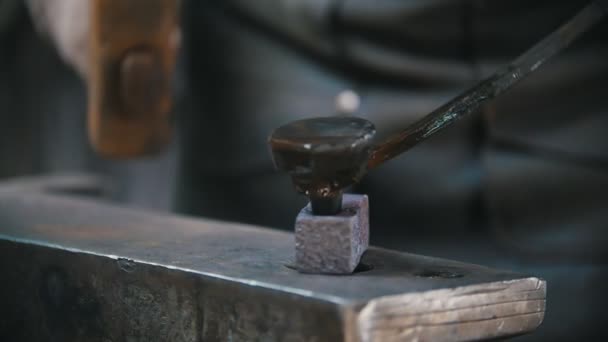 Blacksmith working with hammer on the anvil, man making holes in red hot steel, craft — Stock Video