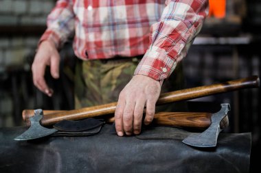 Yeni eksen kavramı deri önlük üzerinde yatıyor. Demirci iş başında