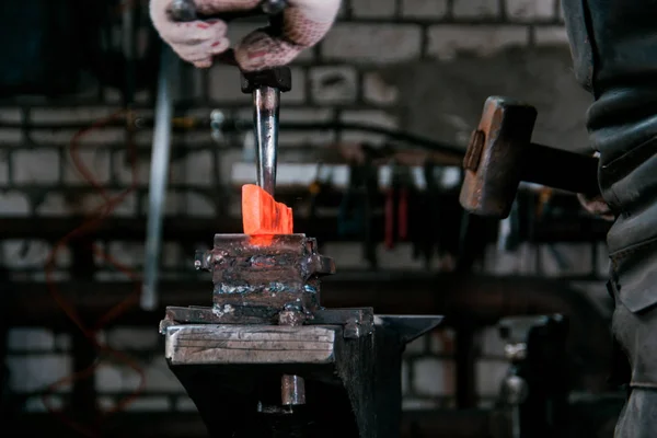Espaço de trabalho do ferreiro. Ferreiro trabalhando com metal quente vermelho em bigorna em uma forja — Fotografia de Stock