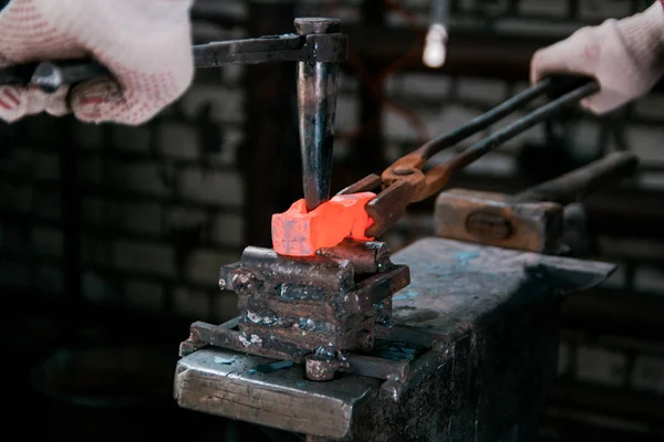 Espaço de trabalho do ferreiro. Ferreiro trabalhando com peça de metal quente vermelho de novo martelo em bigorna em uma forja — Fotografia de Stock