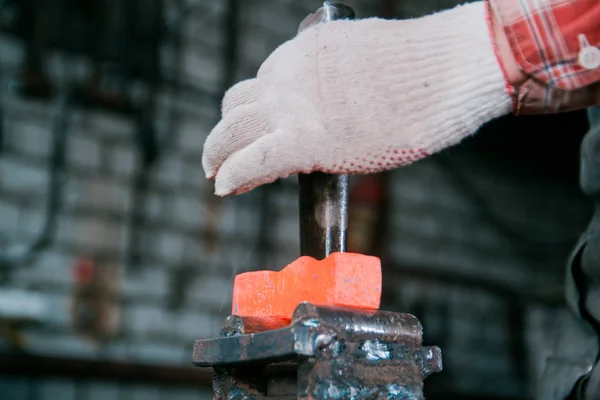 Ferreiro trabalhando com peça de metal quente vermelho de machado na bigorna na forja — Fotografia de Stock