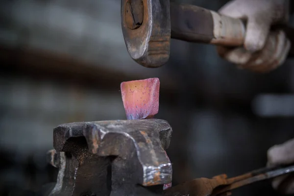 Workspace of blacksmith. Blacksmith working with red hot metal workpiece of new hammer in the vise at the forge