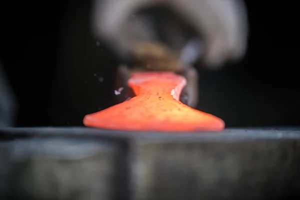 Кузнец и наковальня. Кузнец работает с красным горячим металлом заготовки нового молотка на наковальне в кузнице — стоковое фото