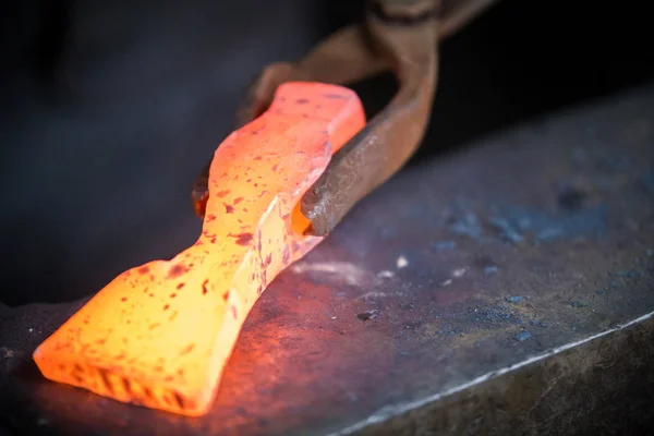 Blacksmith and anvil. Blacksmith working with red hot metal workpiece of new hammer on the anvil — Stock Photo, Image