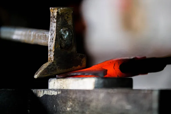 Blacksmith working with red hot metal of new axe on the anvil at the forge Macro photo — Stock Photo, Image