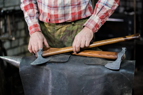 Koncepcja nowej osi znajduje się na skórze w forge. Kowal w pracy — Zdjęcie stockowe