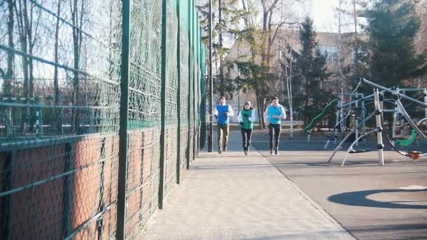 Los jóvenes felices están corriendo en el parque de finales de otoño. Movimiento lento — Vídeo de stock