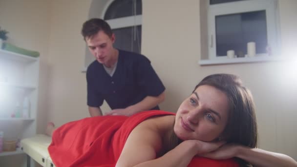 Massage session. Ung kvinna lägger på soffan och ta emot en lugnande massage. Koppla av. Ljus i fokus — Stockvideo