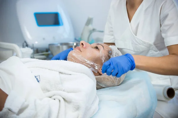 Tratamentos de cosmetologia. Colocar polietileno no rosto . — Fotografia de Stock