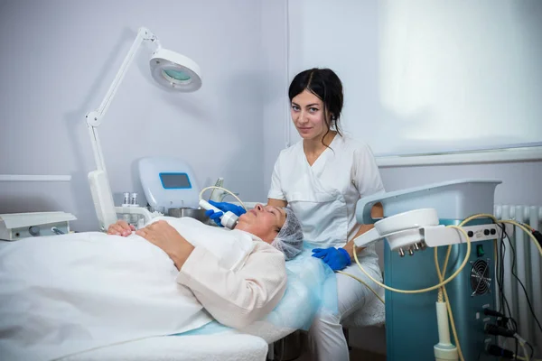 Clinica di cosmetologia. Un cliente che sta seguendo una procedura anti-invecchiamento. Lavorare con uno strumento speciale . — Foto Stock