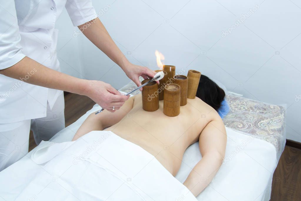 A woman taking a treatment of alternative medicine. Moxotherapy procedure. Burning up a cotton wool