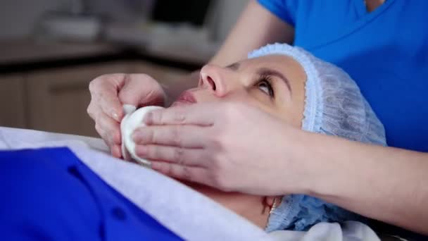 Sessão de massagem. Uma mulher a receber uma massagem facial. Limpando o rosto com almofadas de algodão — Vídeo de Stock