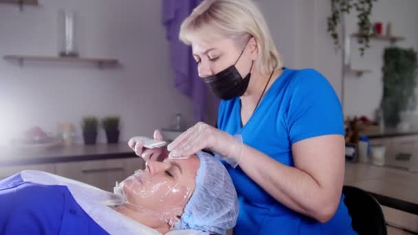 Massage sessie. Een vrouw krijgt een massage van het gezicht. Reiniging van de huid met een spatel. — Stockvideo