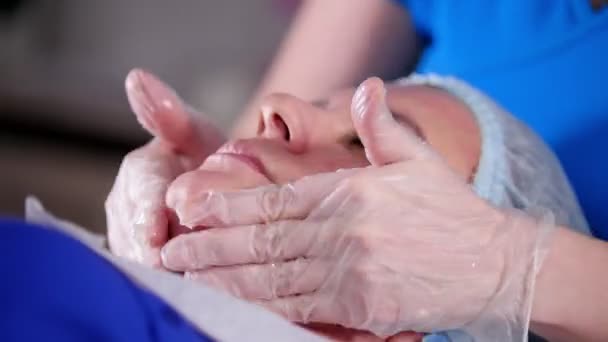 Güzellik Kliniği. Genç kadın ile krem maske yüz masajı masör tarafından alır. — Stok video