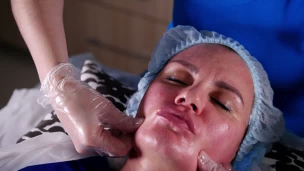 В клинике красоты. Молодая женщина получает расслабляющий массаж лица. Массаж губ и носогубных складок — стоковое видео