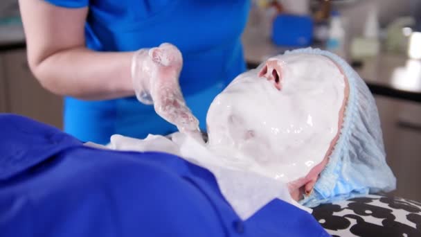 Schönheitsklinik. junge Frau bekommt eine kosmetische Behandlung. Eine Anti-Aging-Flüssigmaske auf das Gesicht schmieren. — Stockvideo