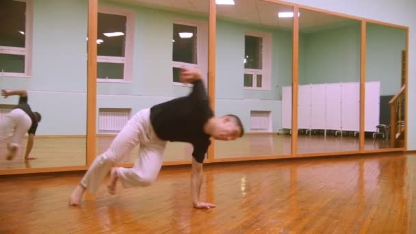 Чоловічий боєць виконує бойові трюки з танцювальними елементами в спортзалі — стокове відео