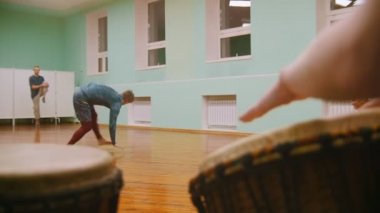 Erkek savaşçı dans elemanları ile dövüş sanatları hileler iki müzik aletleri jembe veya atabaque oynarken arka plan üzerinde gerçekleştirir.