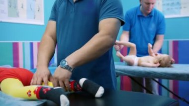 Tıp Kliniği. Serebral felç bozukluğu olan çocuklar ile bir meslek. Fiziksel egzersizleri yapıyor. Bacak kasları Masaj