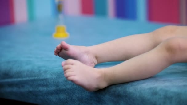 Medizin-Klinik. Ein Arzt arbeitet mit einem kleinen Baby mit zerebraler Lähmung. Füße und Sanduhr aus nächster Nähe — Stockvideo