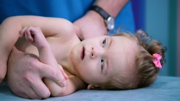 医療センター。脳性麻痺の障害を持つ小さな赤ちゃんと一緒に演習を行う医師。医師を見て、笑みを浮かべて赤ちゃん — ストック動画