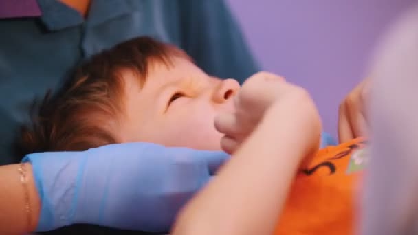 Centro médico. Una doctora masajeando la cara de los bebés. Un bebé con parálisis cerebral. De cerca. — Vídeo de stock