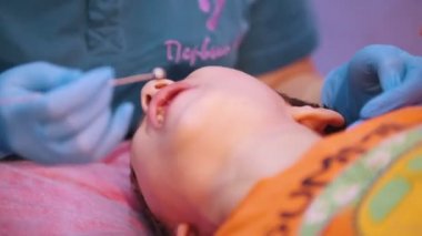 Tıp Kliniği. Beyin felci hastalığı olan bir bebek. Konuşma terapisi, ağız özel araç ile bir kadın çalışıyor