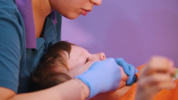 Clínica médica. Um bebé com paralisia cerebral. Uma mulher termina a massagem fonoaudiológica — Vídeo de Stock