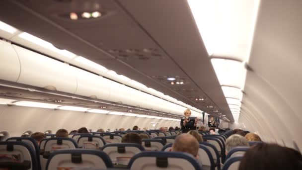 俄罗斯, 莫斯科。8-11-2018. 谢列梅捷沃机场: 飞机。飞机的乘客机舱。空姐解释了安全措施。监视她的乘客 — 图库视频影像