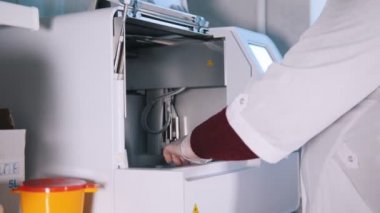 Sağlık kliniği. Hemşire kan örnekleri makineden alır