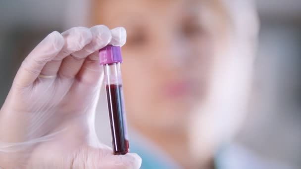 Clínica médica. Enfermeira segurando um tubo de teste com amostra de sangue. Fechar — Vídeo de Stock