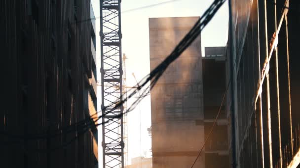Lugar de construcción. Grúa torre de trabajo. El polvo se eleva en el aire. Colgar cables en el primer plano — Vídeo de stock