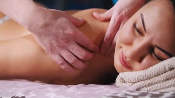 Massage behandling. En leende kund lägger sig på soffan och ta emot massage. Närbild — Stockvideo