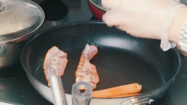 Ett kök i caféet. Att göra en engelsk frukost i pannan. Tillägger bönor till bacon och korv — Stockvideo