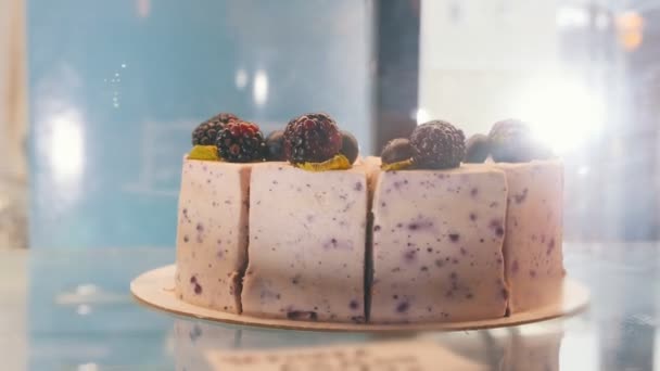 A blackberry cake behind the shop window. Blackberries on the top of the cake. — Stock Video