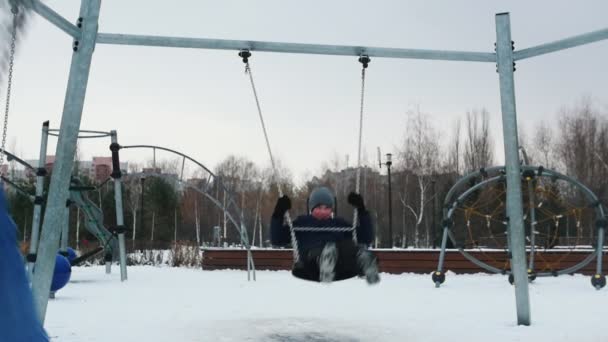 Two young kids having fun on the playground. Swinging in slow motion — Stock Video