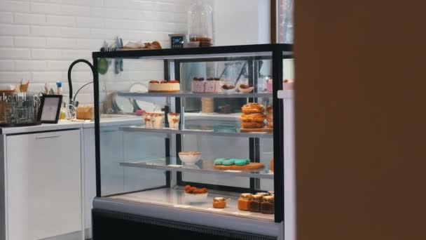 Une boulangerie. Un homme à lunettes écrit quelque chose. Une vitrine avec des bonbons . — Video