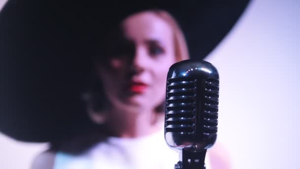 En kvinna i stor svart elegant hatt tar tag i mikrofonen och börjar sjunga — Stockvideo